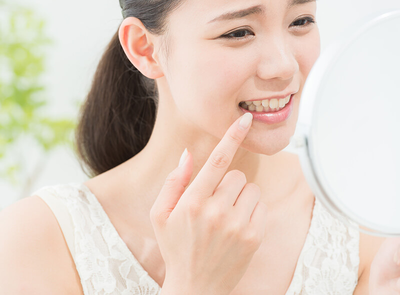 鏡を見ながら歯をチェックする女性